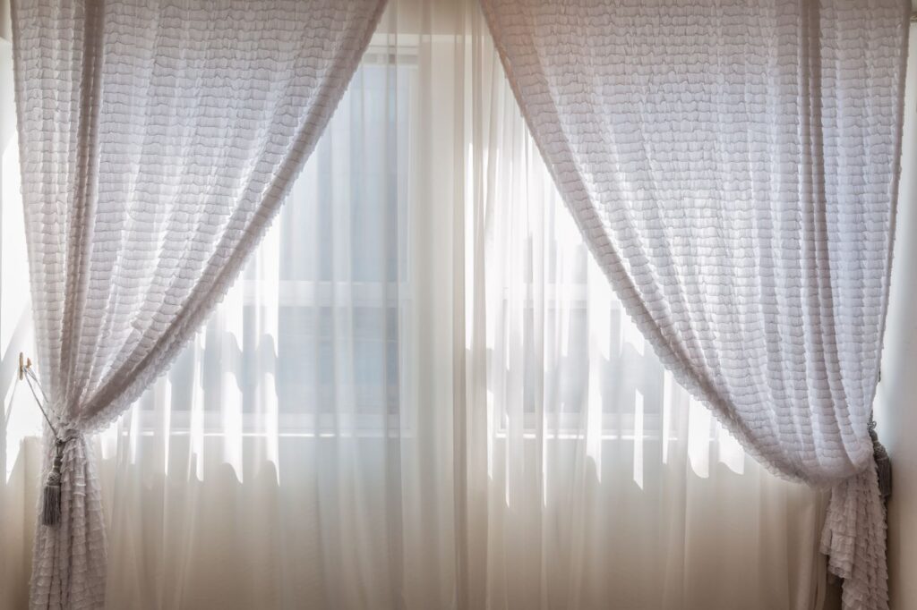 Sunlight coming through white curtains at a bedroom window