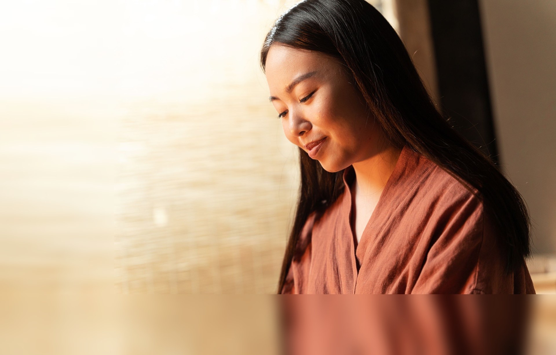 A young woman sitting quietly in warm window light at home