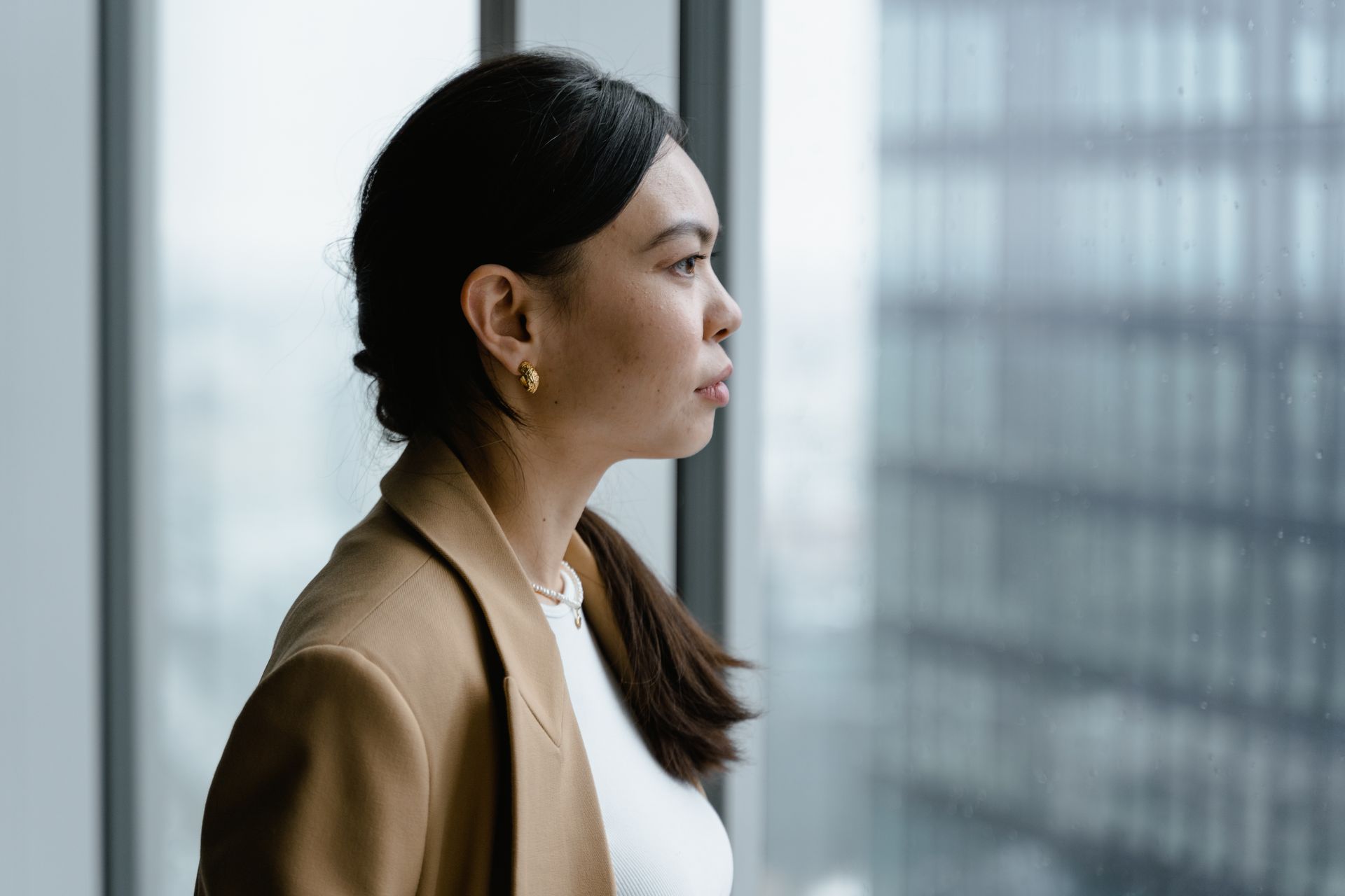 A woman in her forties looking thoughtfully out of a window